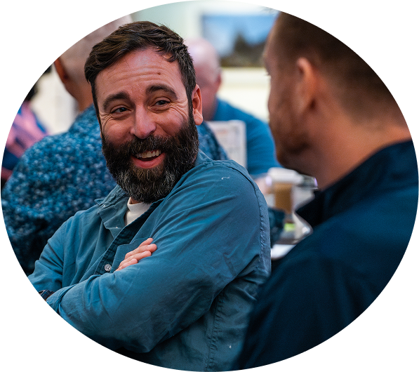 A bearded man smiling and laughing with his colleague