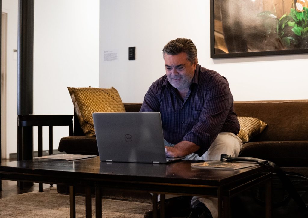 A man sitting on the couch working on his laptop